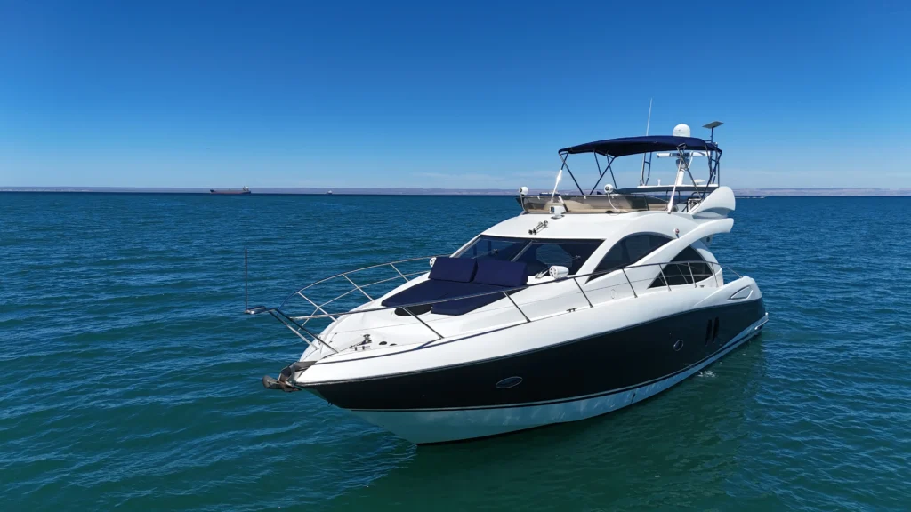 White motor yacht anchored on calm turquoise sea under a clear blue sky, viewed from the bow side dock.