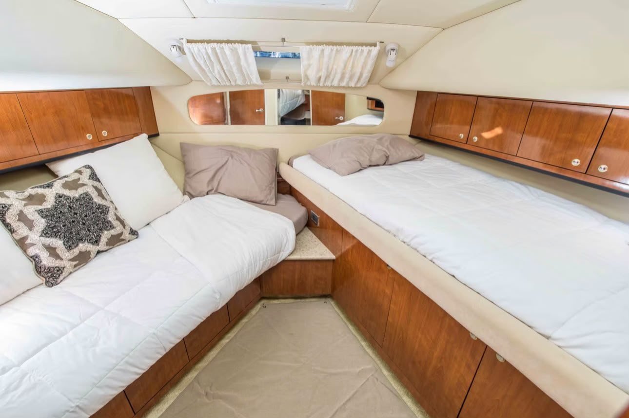 Guest cabin aboard Cabo2Vegas with twin berths and cherry wood cabinets